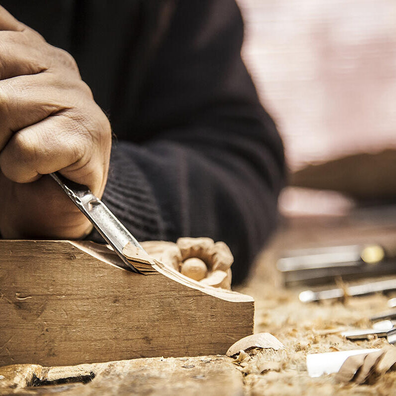 An engraver is carving a piece of wood frame